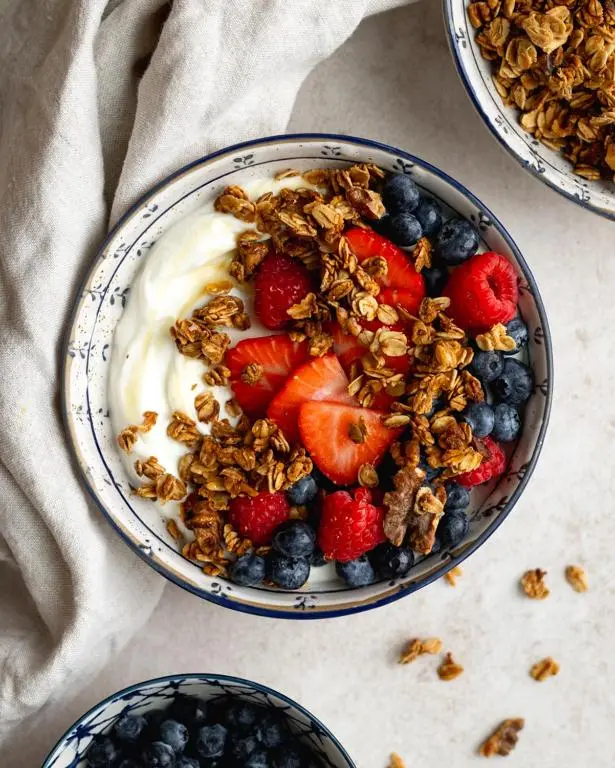 a bowl of fruit and yogurt with berries and granola at Waterside House B&B in Ullapool