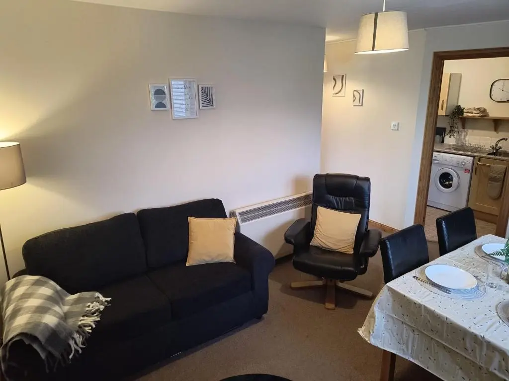 a living room with a couch and chairs and a table at Highland Getaway in Inshes