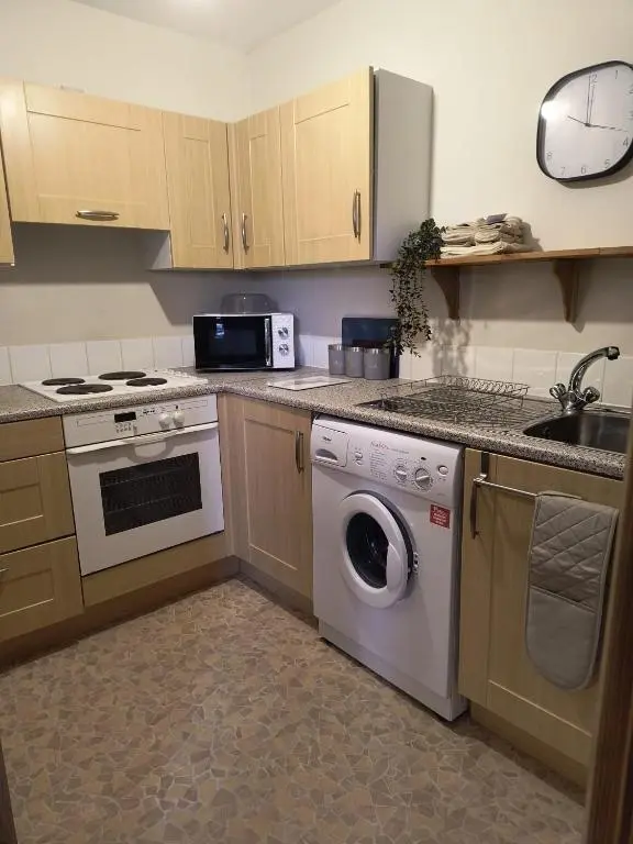 a kitchen with a washing machine and a microwave at Highland Getaway in Inshes