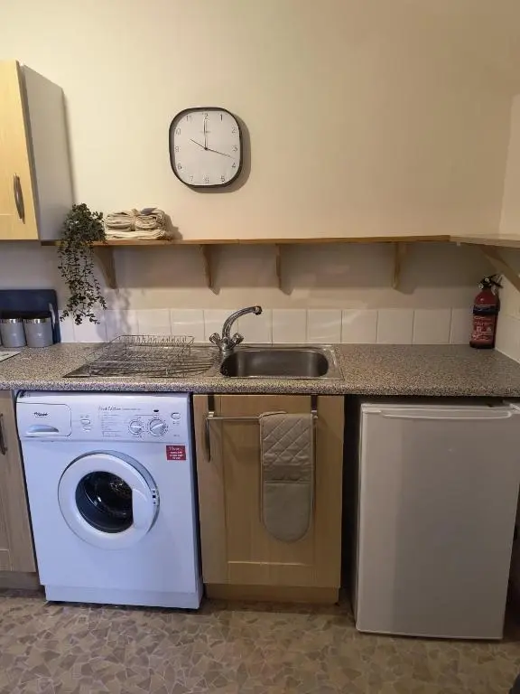 a kitchen with a sink and a washing machine at Highland Getaway in Inshes