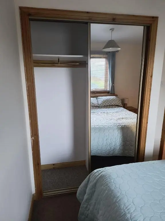 a bedroom with a mirror next to a bed at Highland Getaway in Inshes