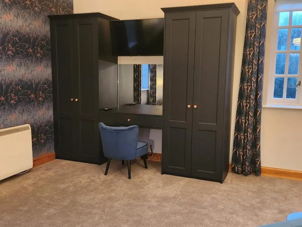 a bedroom with a desk and a cabinet and a chair at Recently refurbished former art studio in Rothiemay Station