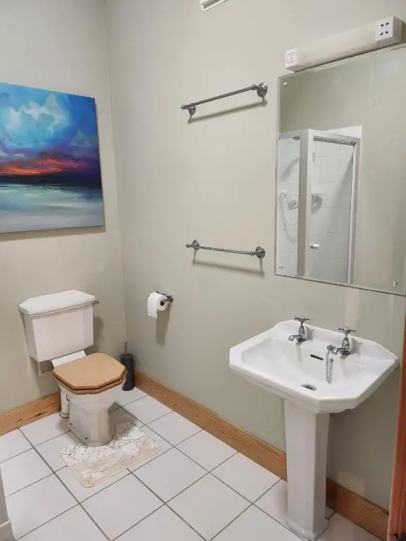 a bathroom with a sink and a toilet and a mirror at Recently refurbished former art studio in Rothiemay Station