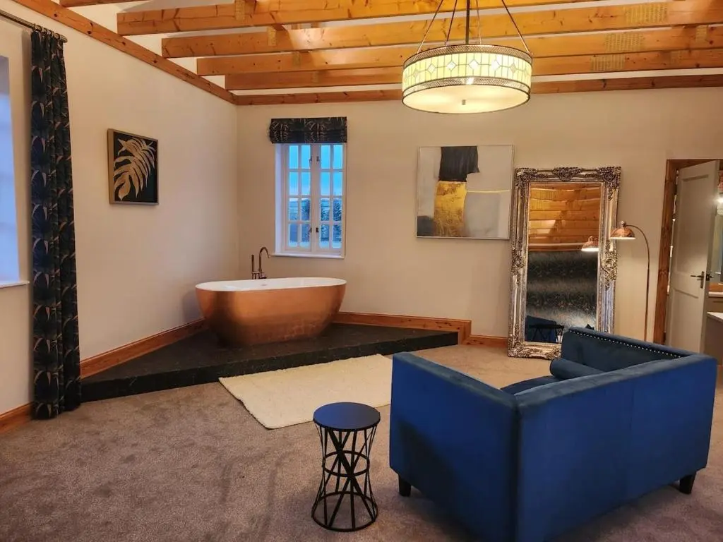 a large bathroom with a tub and a blue couch at Recently refurbished former art studio in Rothiemay Station
