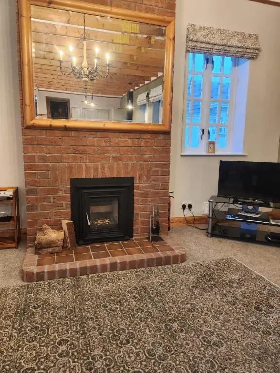 a living room with a brick fireplace and a television at Recently refurbished former art studio in Rothiemay Station