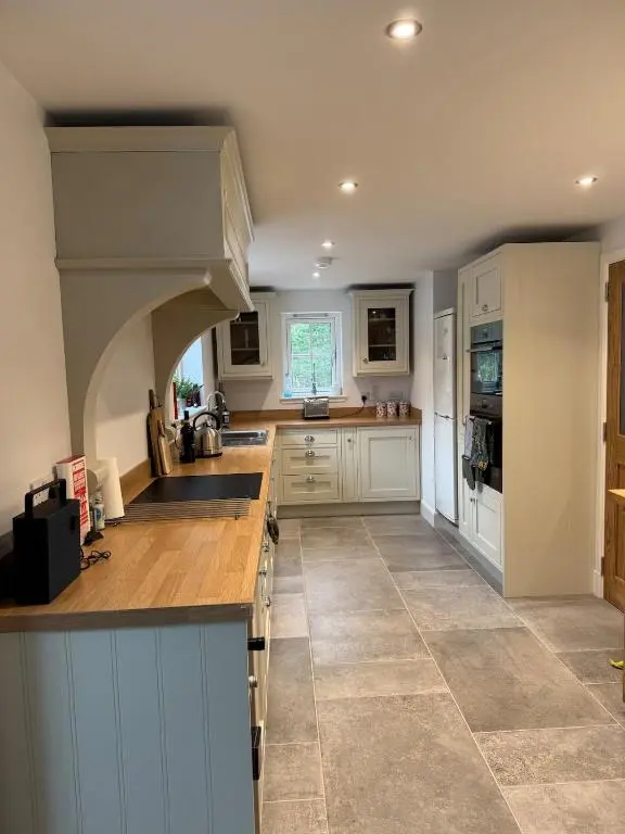 a large kitchen with white cabinets and a counter top at Cosy Highland Cottage in the Woods on Royal Deeside in Coldstone