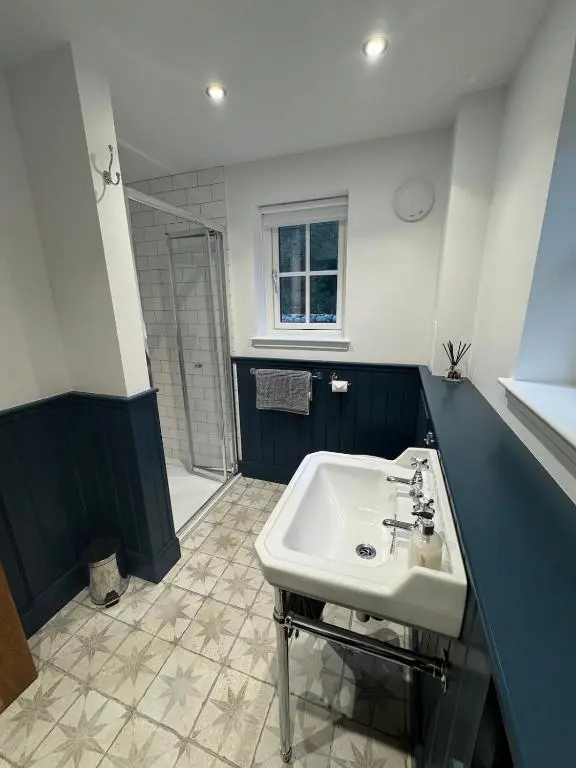a bathroom with a white sink and a shower at Cosy Highland Cottage in the Woods on Royal Deeside in Coldstone
