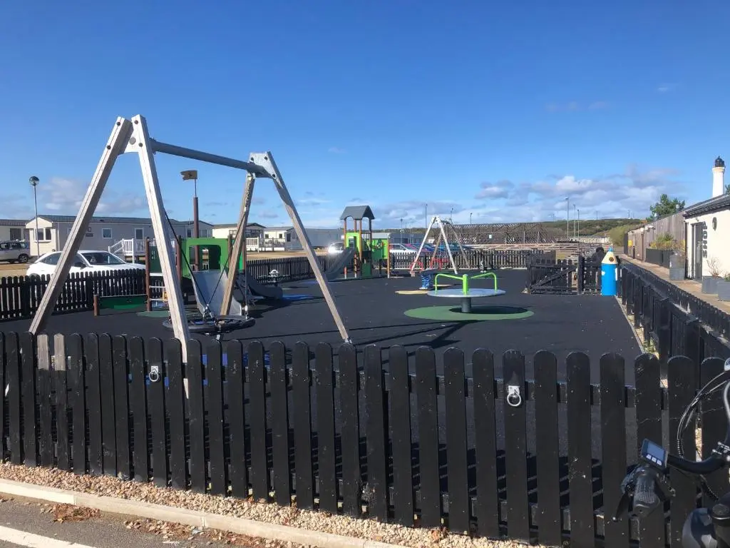 a playground with two swings and a fence at Dunes Escape in Lossiemouth
