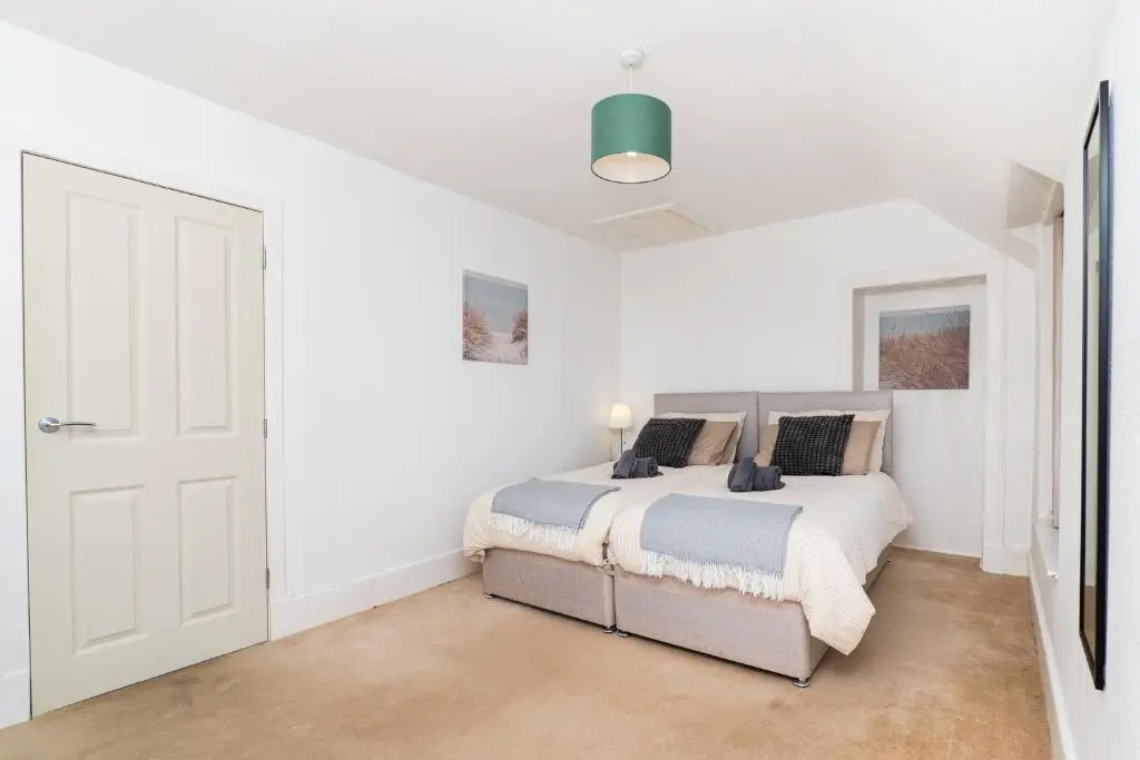 a white bedroom with a bed and a door at Charming 1-Bed Coastal Cottage by Holiday Homes in Portgordon