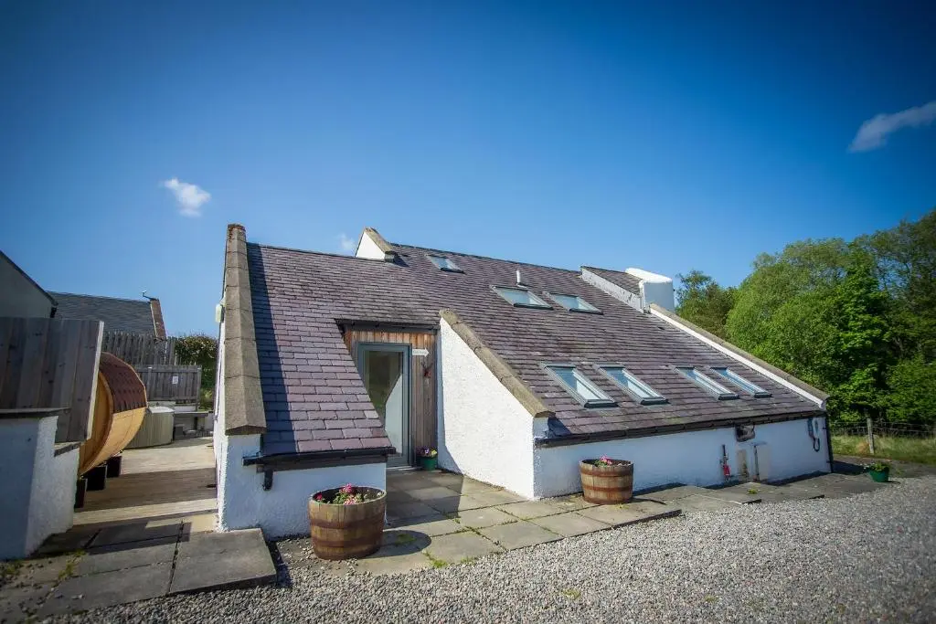 a small white house with two pots in front of it at Kirkstone Lodge in Insh