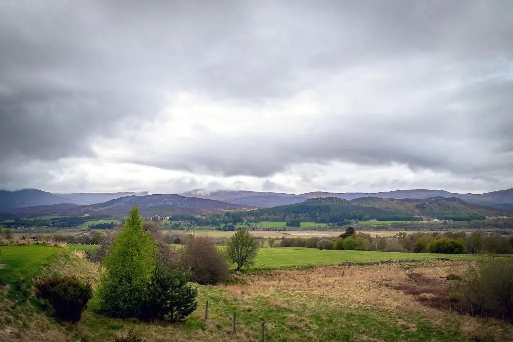 a green field with mountains in the background at Kirkstone Lodge in Insh