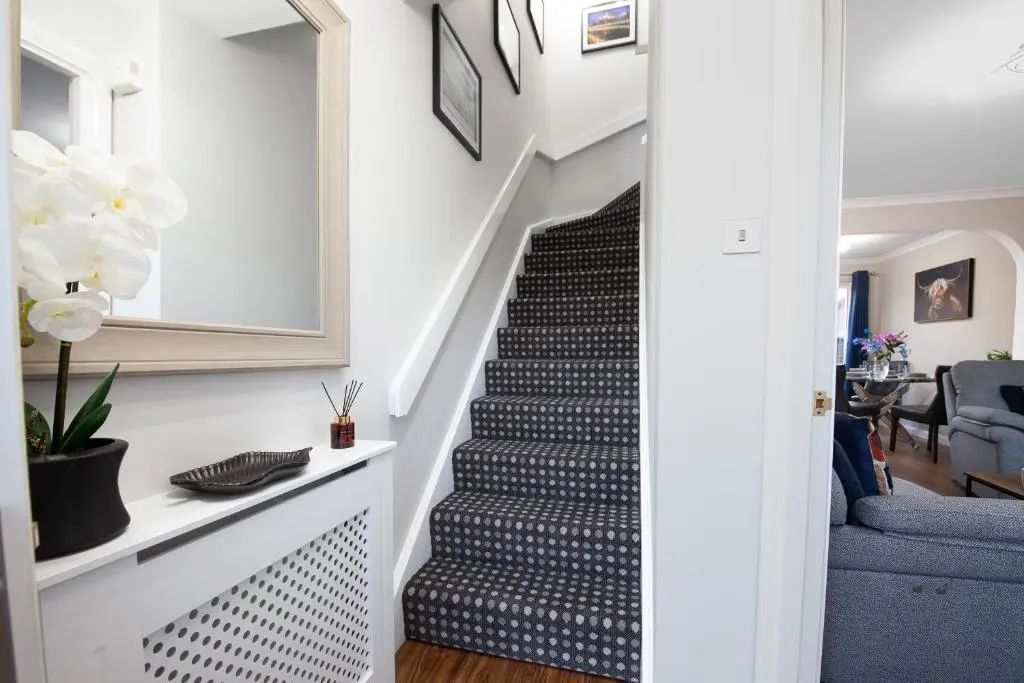a staircase in a living room with a blue couch at Castle Heather 2 Bedroom Holiday Home in Inshes