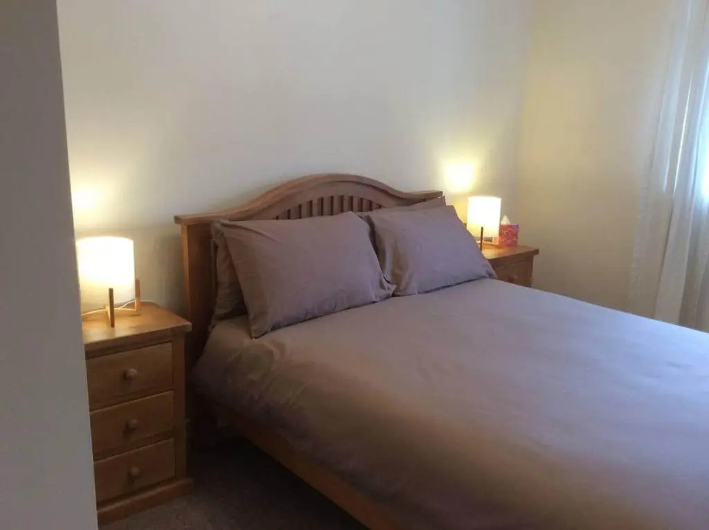 a bedroom with a bed with two nightstands and two lamps at Macdonald Apartment 11C Greig St Inverness IV3 5PT in Inverness