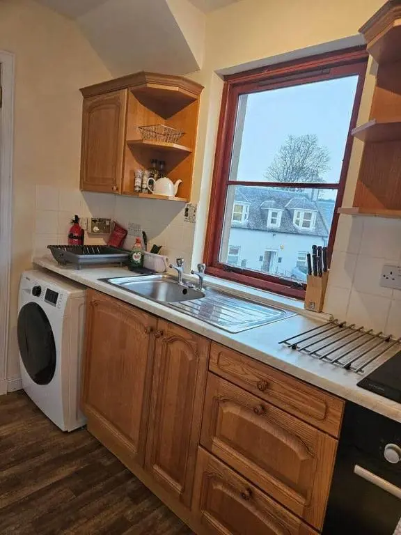 a kitchen with a sink and a washing machine at 5 Ardross Court, 20 Ardross St. Inverness IV3 5NH in Inverness