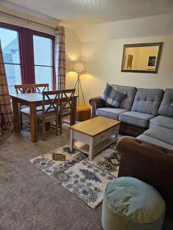 a living room with a couch and a table at 5 Ardross Court, 20 Ardross St. Inverness IV3 5NH in Inverness