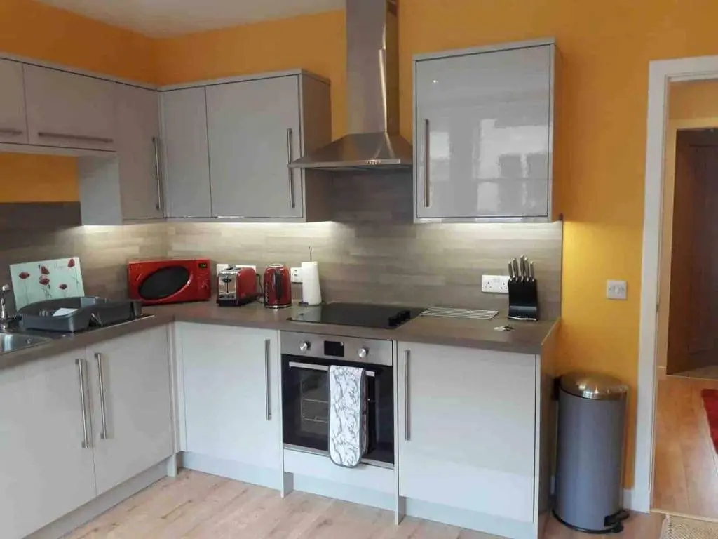 a kitchen with white cabinets and a stove top oven at Macdonald Apartments 9C Greig St Inverness IV3 5PT in Inverness