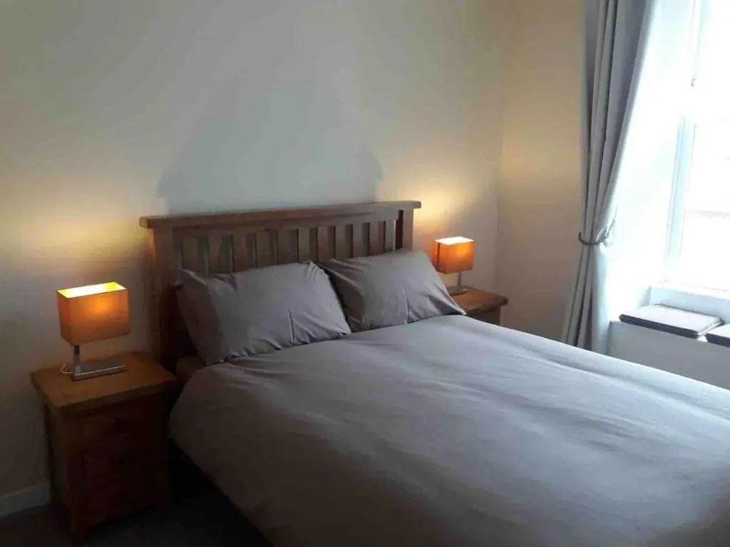 a bedroom with a bed with two lamps on tables at Macdonald Apartments 9C Greig St Inverness IV3 5PT in Inverness
