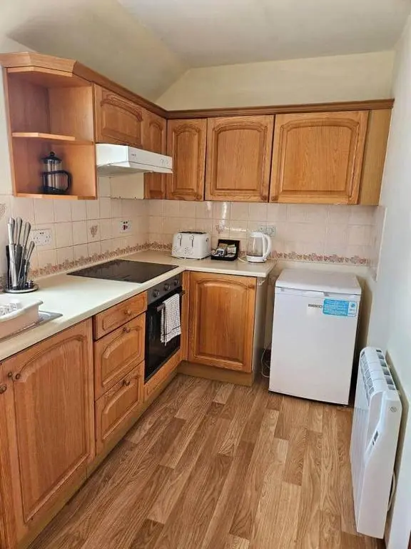 a kitchen with wooden cabinets and a white refrigerator at 8 Ardross Court 20 Ardross St. Inverness IV3 5NH in Inverness