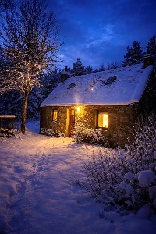 a stone house with lights on it in the snow at bochruben in Inverness