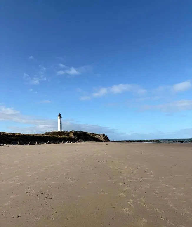 a beach with a lighthouse in the background at B17 SilverSands Escape in Lossiemouth