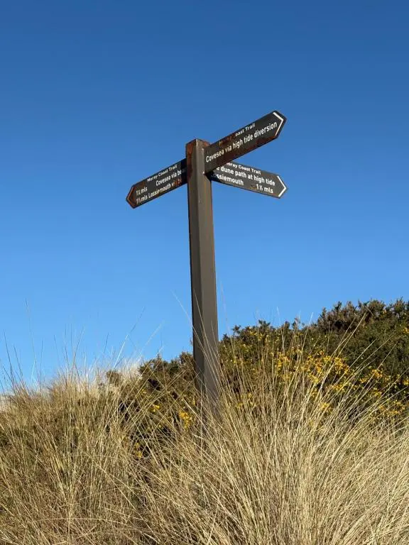 a wooden cross with signs on top of a field at B17 SilverSands Escape in Lossiemouth