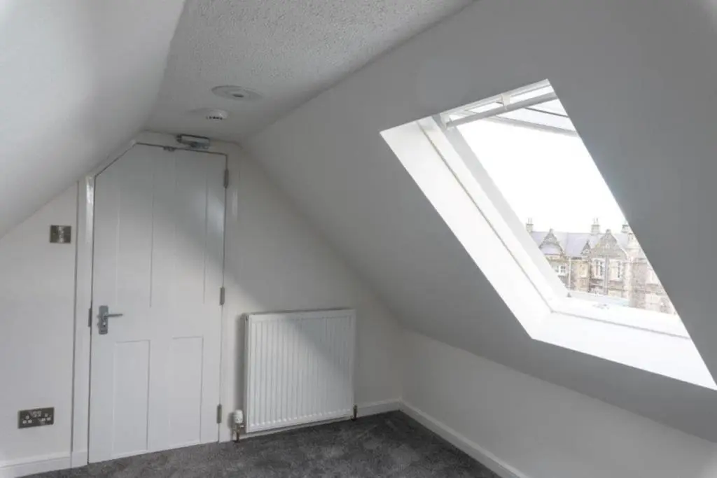 an attic room with a large window and a door at Josies House in Banff
