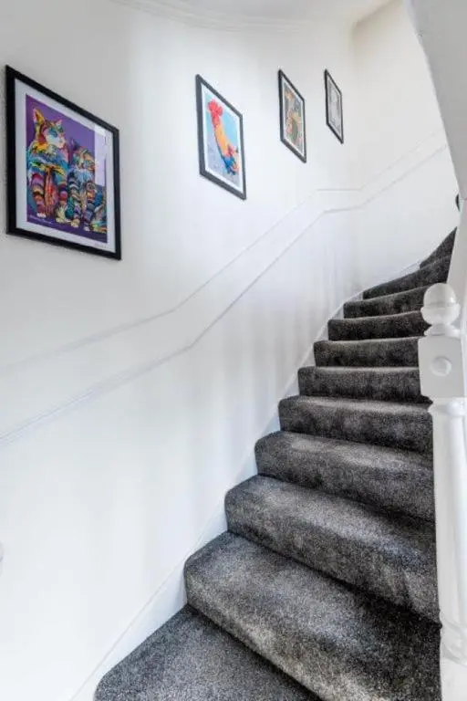 a staircase with grey carpet and framed pictures on the wall at Josies House in Banff