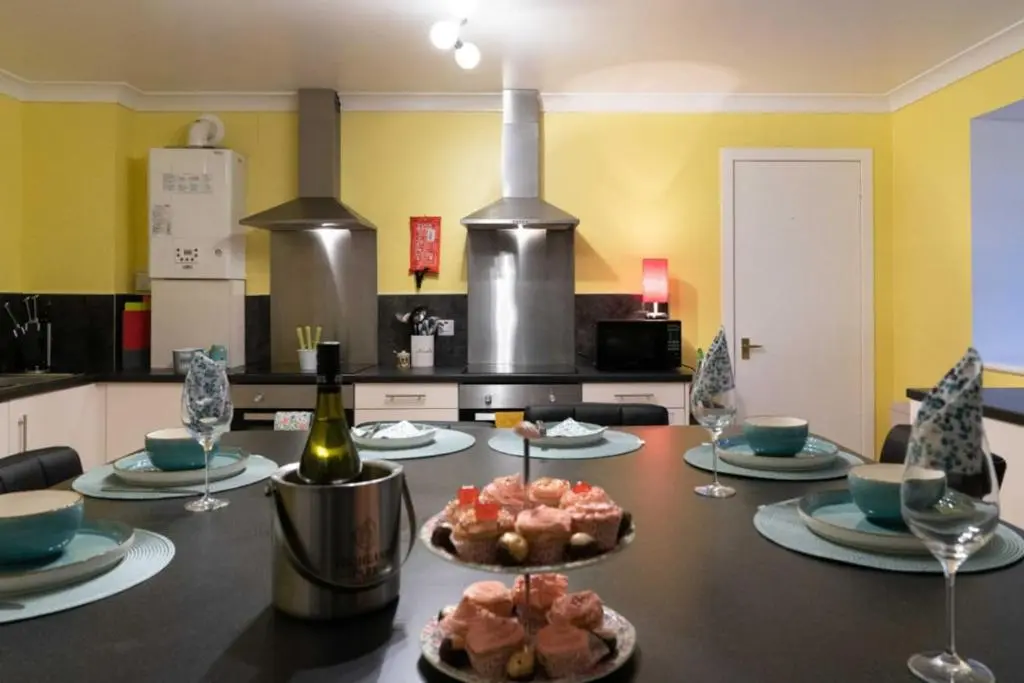 a kitchen with a table with food and wine glasses at Dunedin House in Huntly