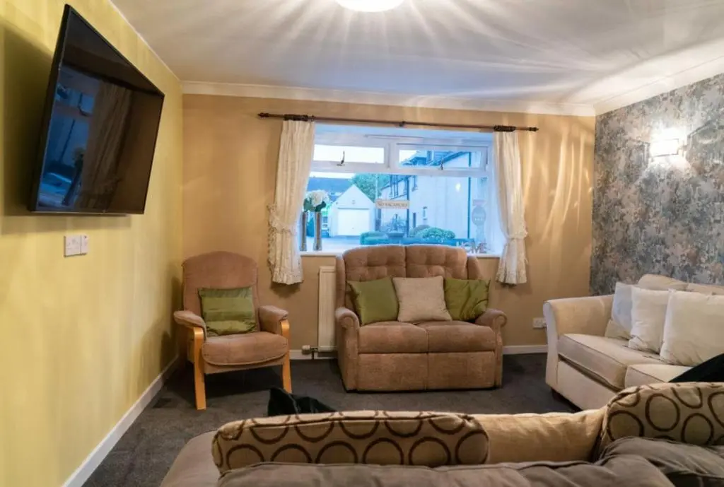 a living room with a couch and chairs and a tv at Dunedin House in Huntly