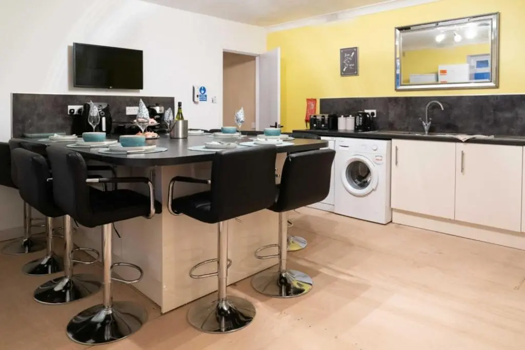 a kitchen with a table with chairs and a washing machine at Dunedin House in Huntly