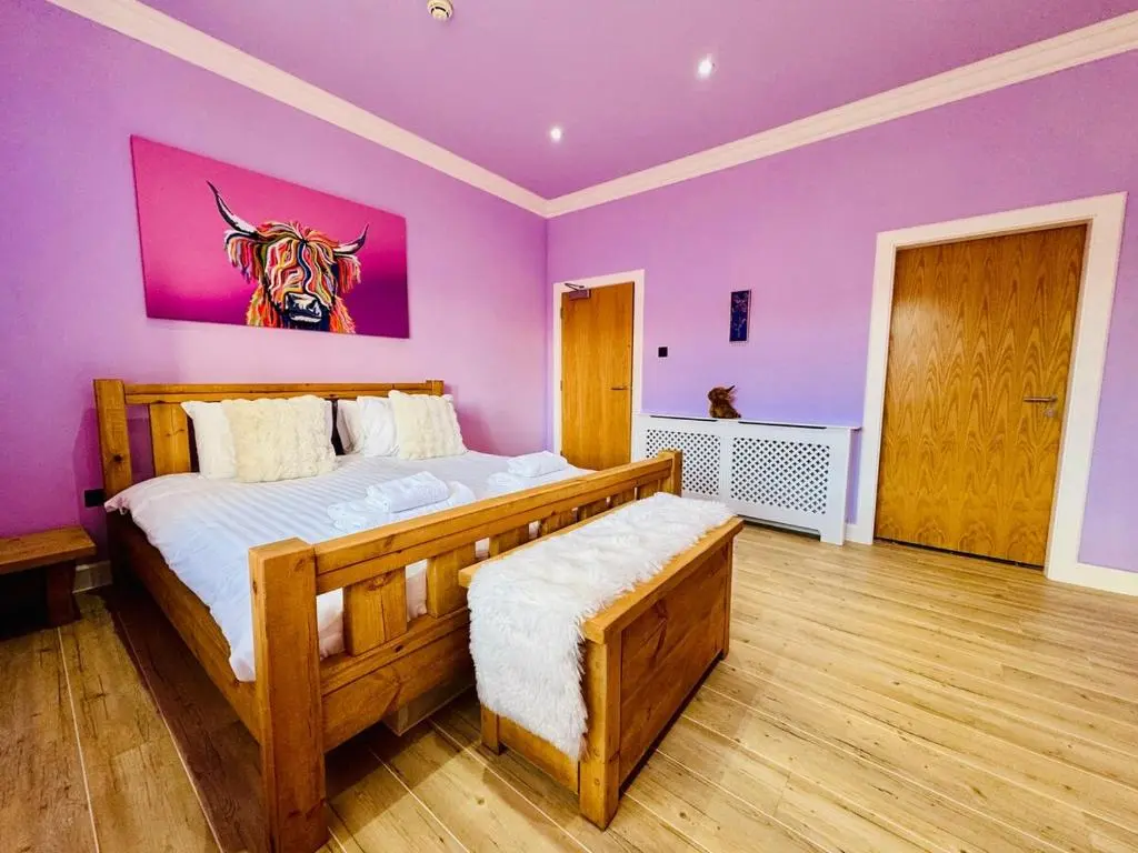 a bedroom with a large bed with a purple wall at Entirely New Monastery Renovation on Loch Ness in Fort Augustus