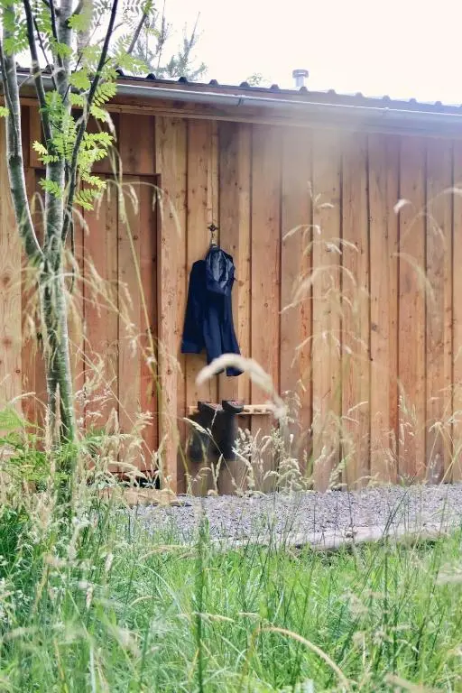 a black jacket hanging on a wooden fence at Bespoke Wood Cabin - Loch Ness in Inverfarigaig