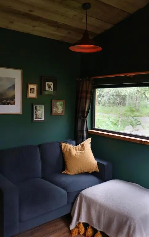 a blue couch in a room with a window at Bespoke Wood Cabin - Loch Ness in Inverfarigaig