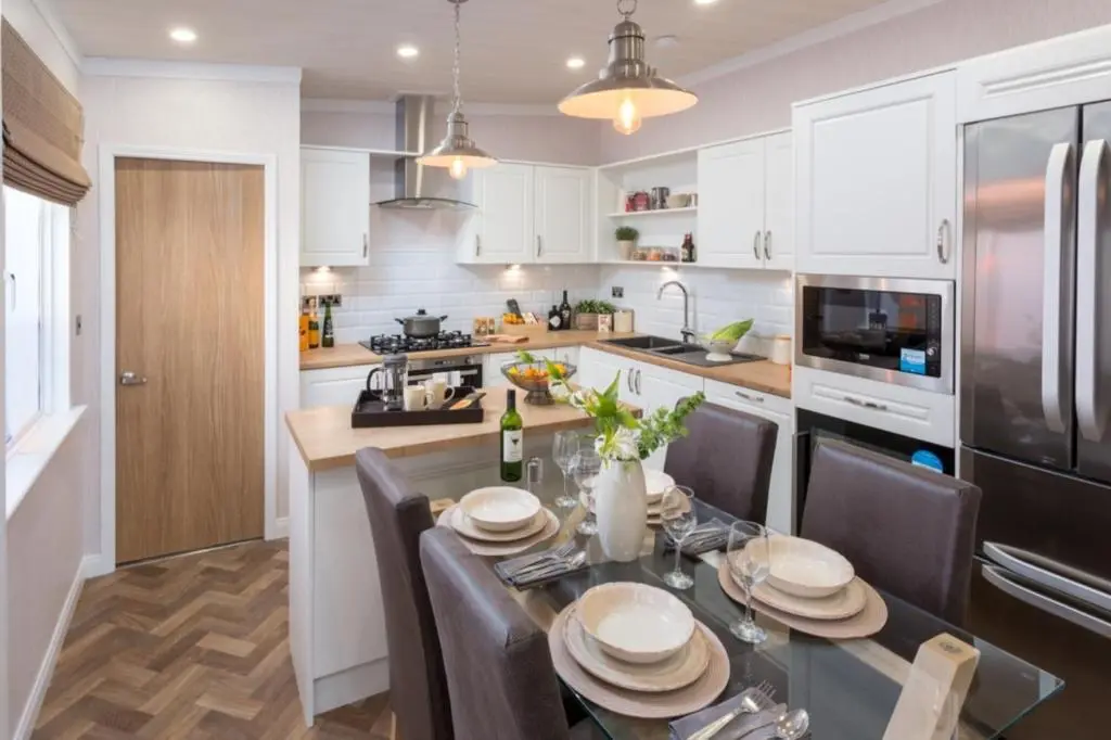 a kitchen with a table with chairs and a refrigerator at Lyndale Lodge