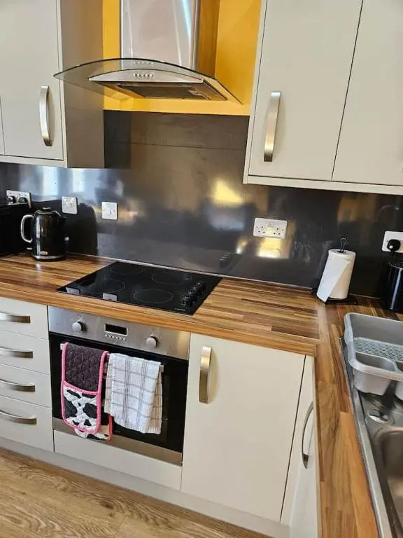 a kitchen with white cabinets and a stove top oven at City center apartment in Inverness