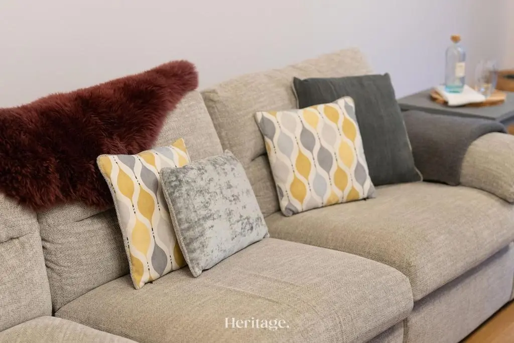 a couch with pillows on it in a living room at The Steading Family Friendly Getaway in Peterhead