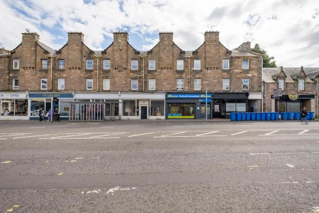 an empty street in front of a large brick building at 2 Bed Central Apart - May Court in Inverness