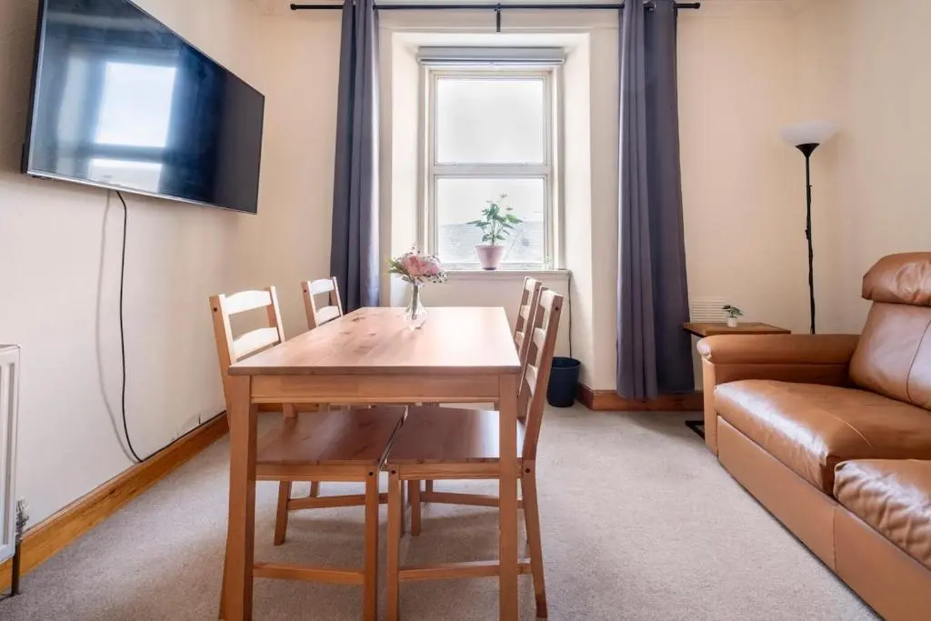 a living room with a table and chairs and a couch at 2 Bed Central Apart - May Court in Inverness
