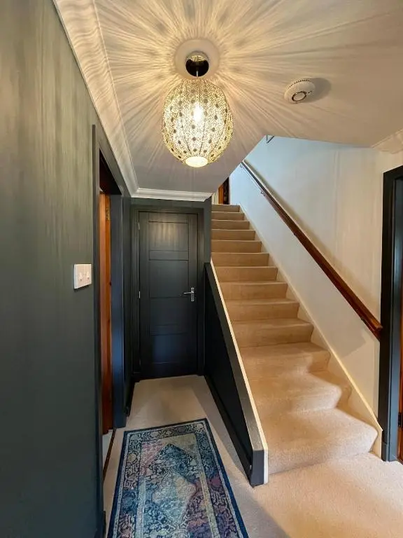 a hallway with a staircase and a chandelier at Freeburn Lodge - Tomatin in Tomatin