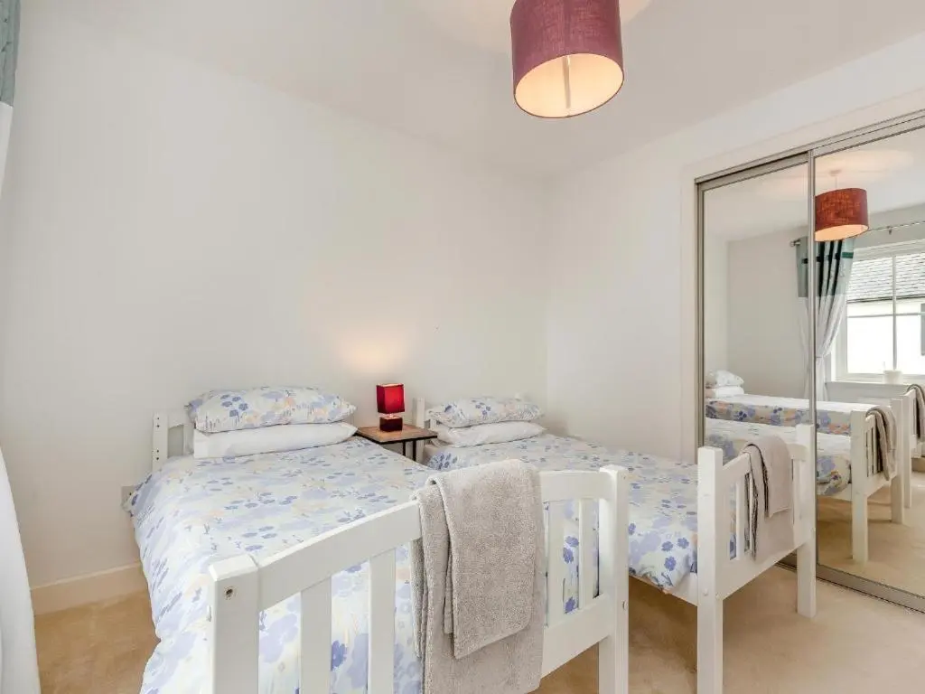 a white bedroom with three beds and a mirror at One The Loan in Inverness