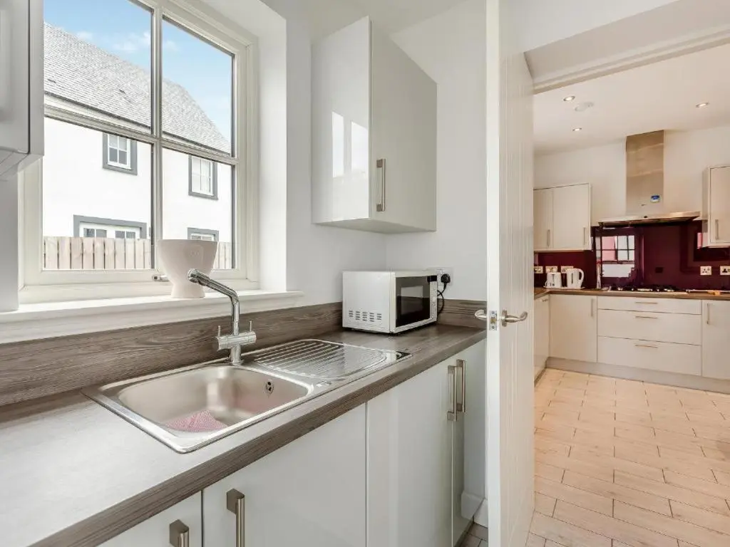 a white kitchen with a sink and a window at One The Loan in Inverness
