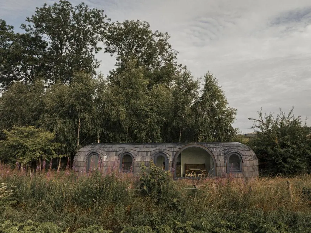 an old brick building in a field with trees at Boath Cabin in Auldearn