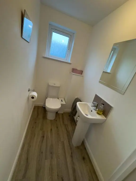 a bathroom with a toilet and a sink and a mirror at Skibo Place House in Inshes