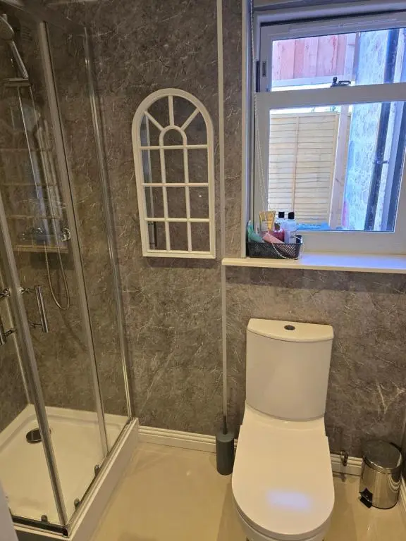 a bathroom with a toilet and a shower and a window at Nanny bambi's three bedroom's in Inverness