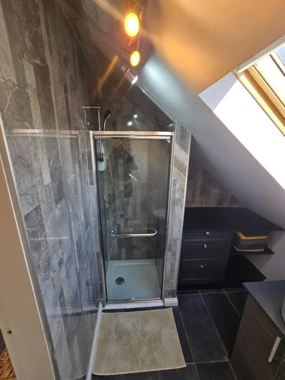 a bathroom with a shower in a attic at Nanny bambi's three bedroom's in Inverness