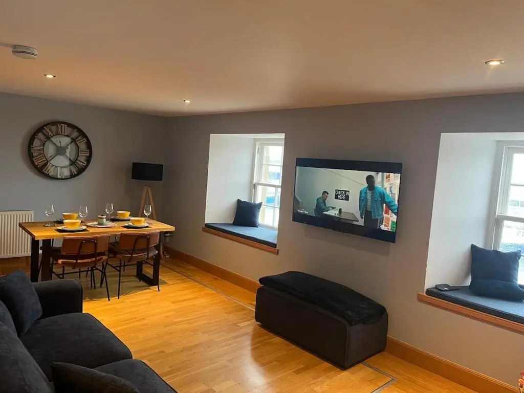 a living room with a couch and a tv on the wall at Harbour Haven in Burghead