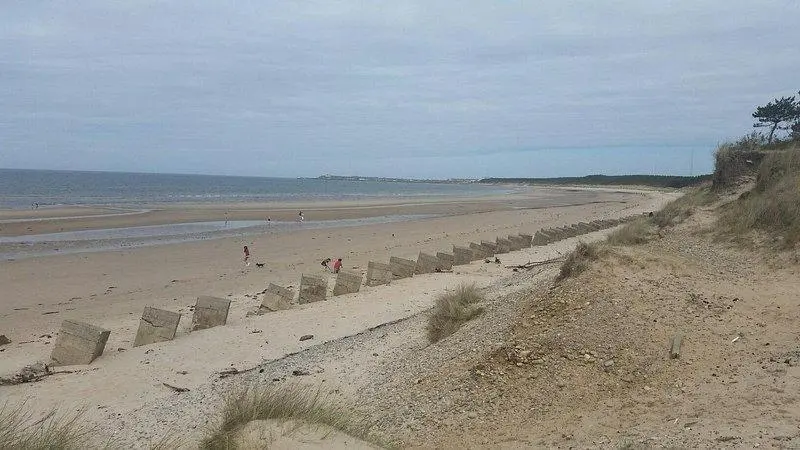 a beach with people walking on the sand at Harbour Haven in Burghead