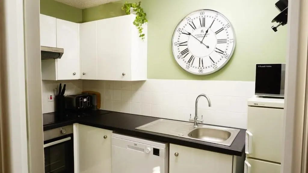 a kitchen with a clock on the wall and a sink at Cosy flat in Inverness