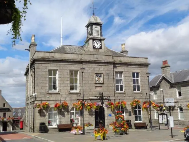 an old building with a clock tower on top of it at Morris Gardens Apartments in Oldmeldrum