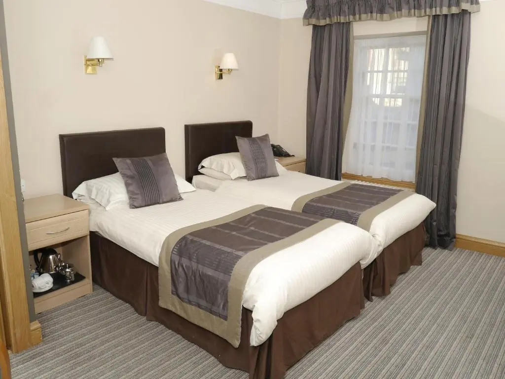 a hotel room with two beds and a window at Burnett Arms Hotel in Banchory